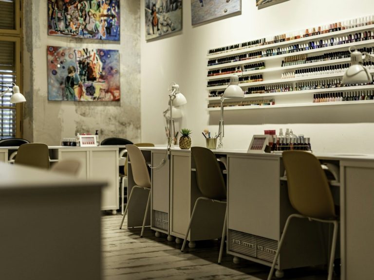 Interior de un salón de manicura con mesas, sillas y obras de arte en las paredes.