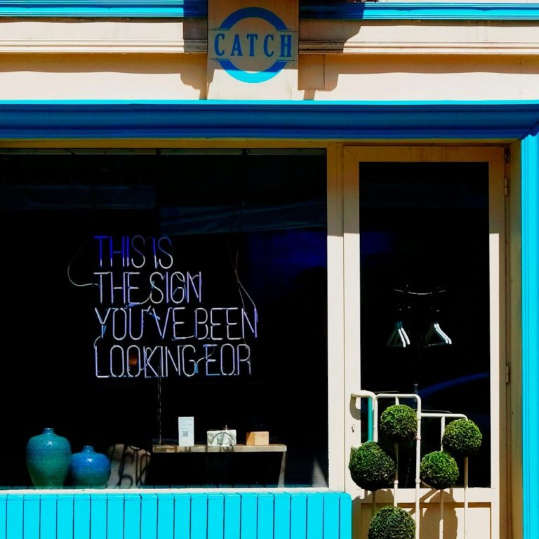 Tienda con un letrero que dice "¡Es lo que has estado buscando!" en un fondo brillante.